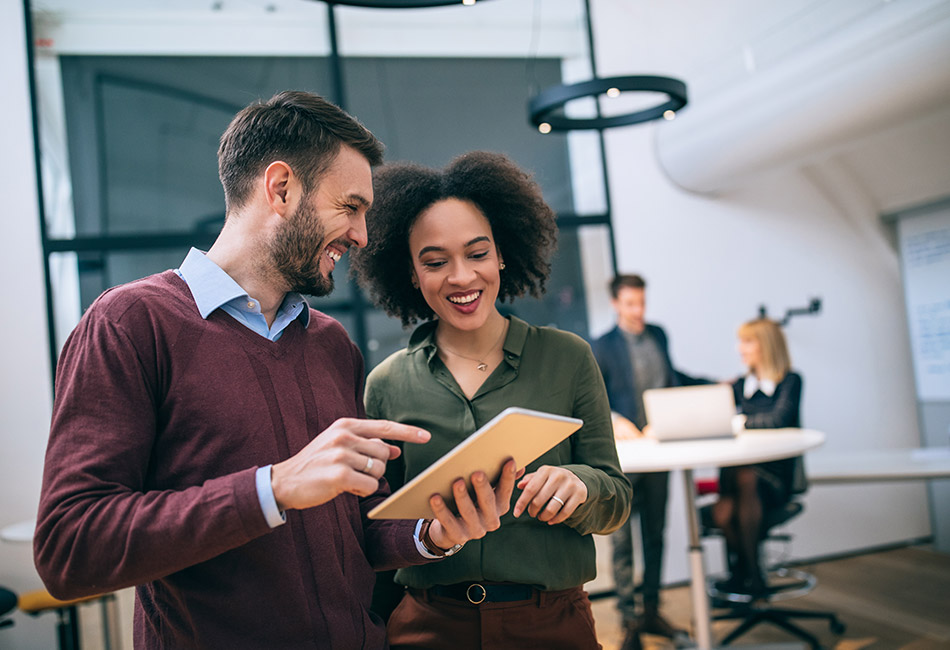 Caucasian man and African American woman looking at iPad in office