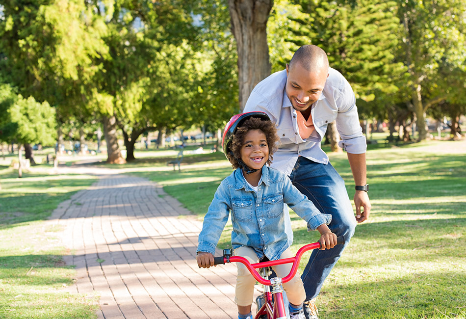 African American dad teaching daughter to ride bike