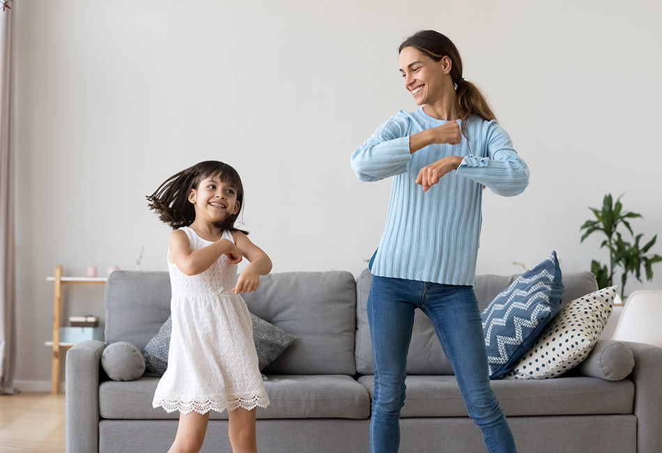 Hispanic mother and daughter dancing at home