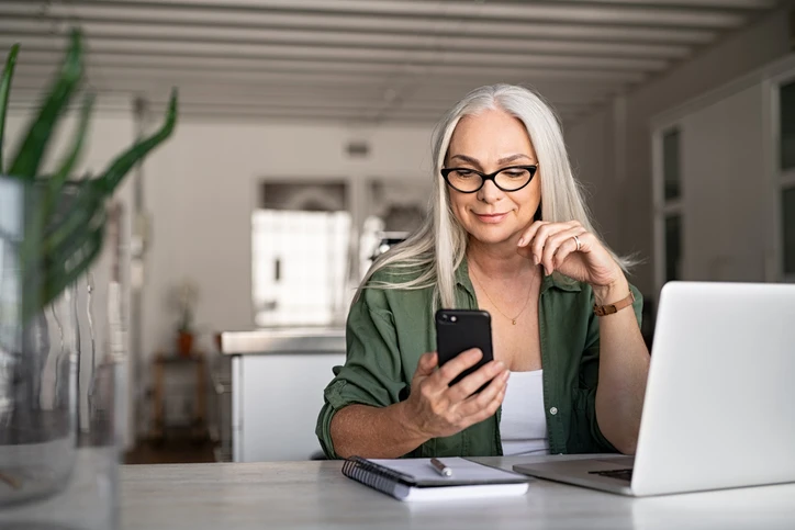 older woman using cell phone and laptop