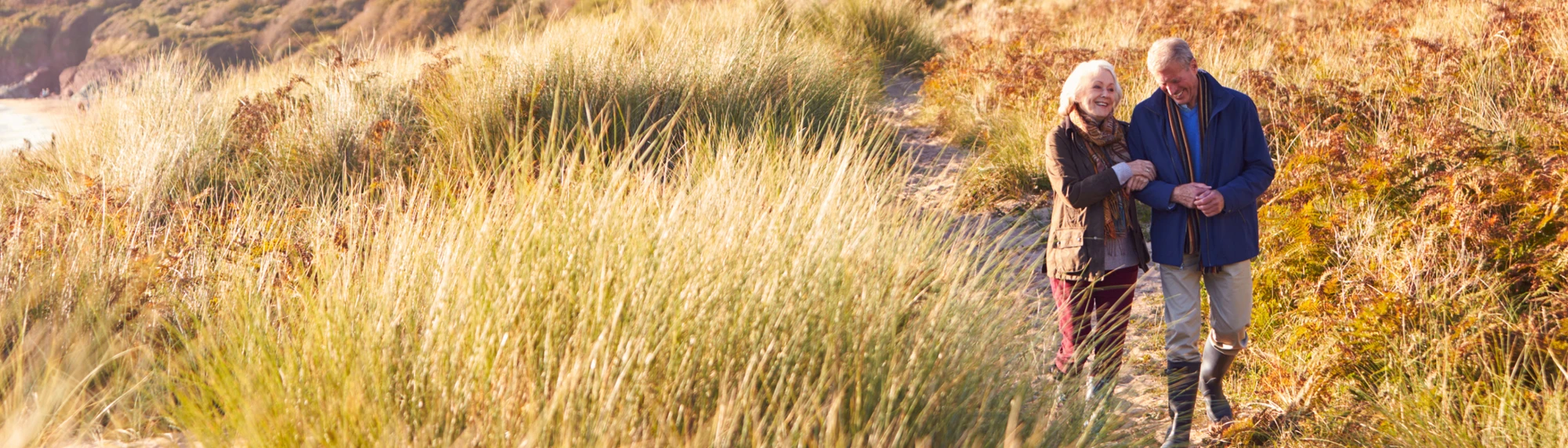 caucasian couple walking through sand dunes