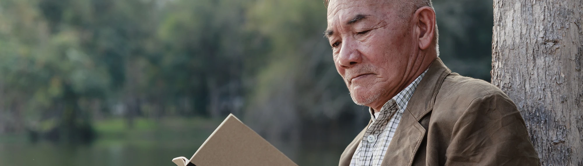 older asian man reading outside
